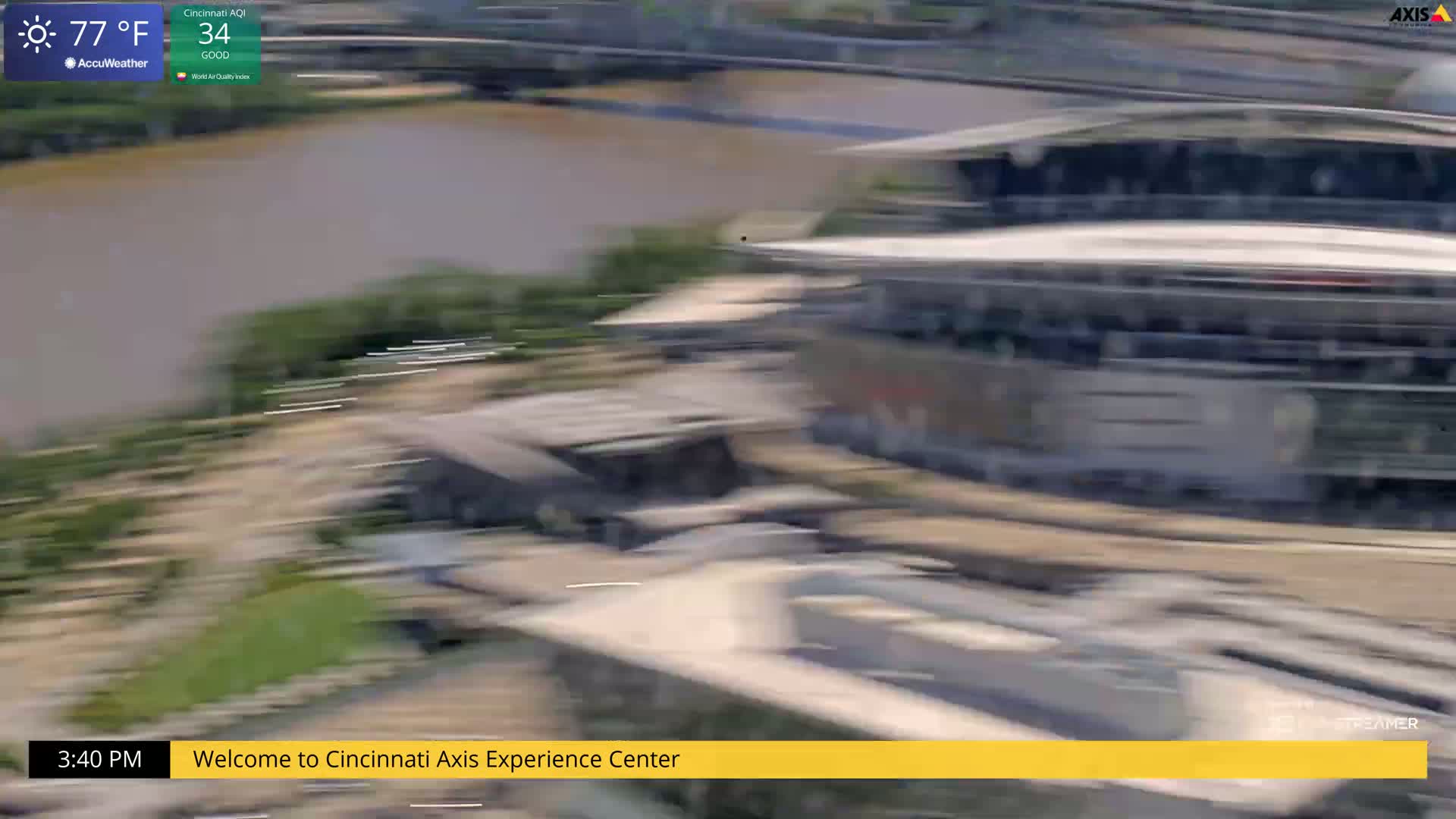 A blurry, high-angle view shows a large structure near a body of water on a sunny 77°F day.