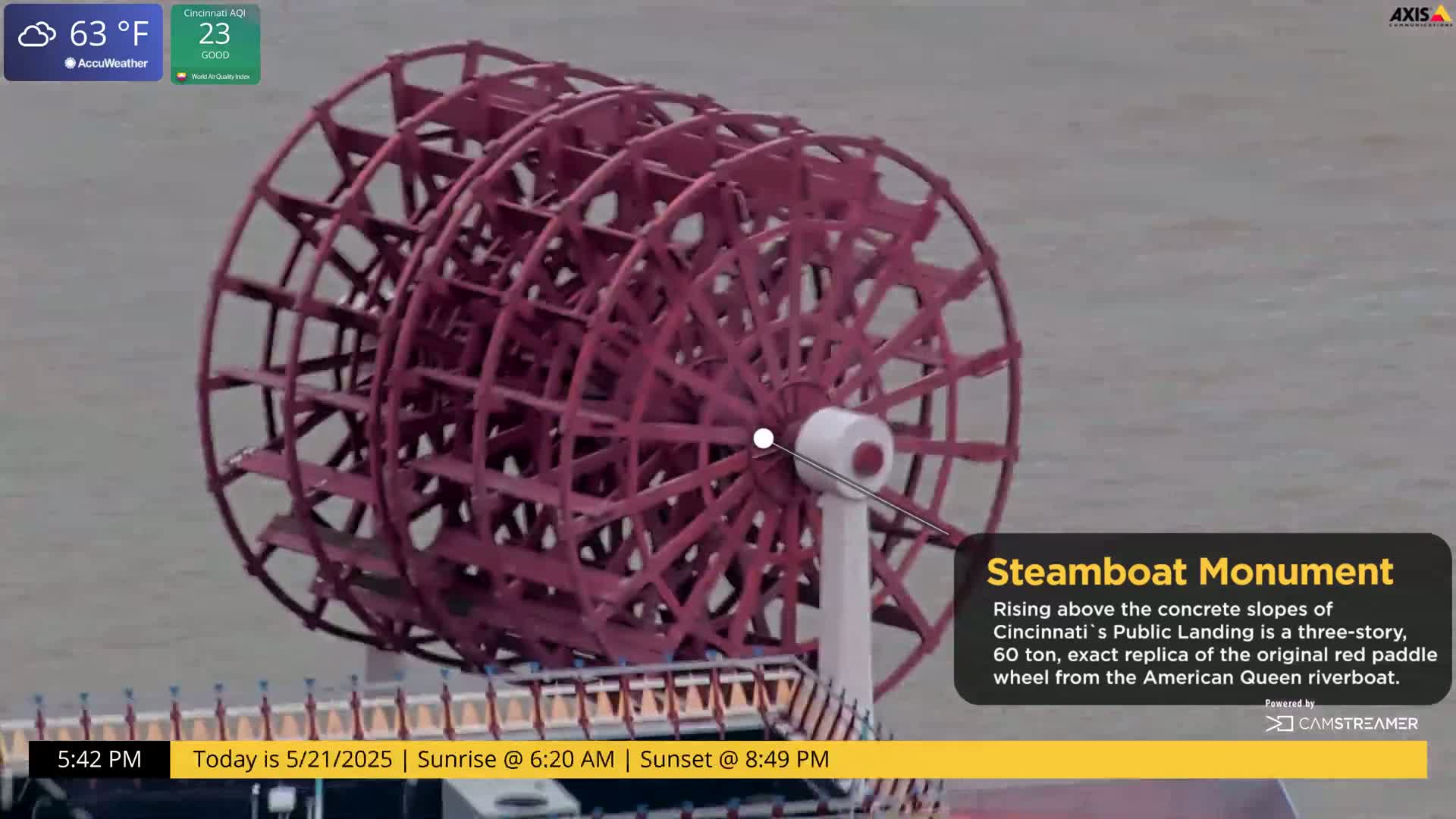 A large, red paddle wheel steamboat monument stands against a gray, overcast sky.