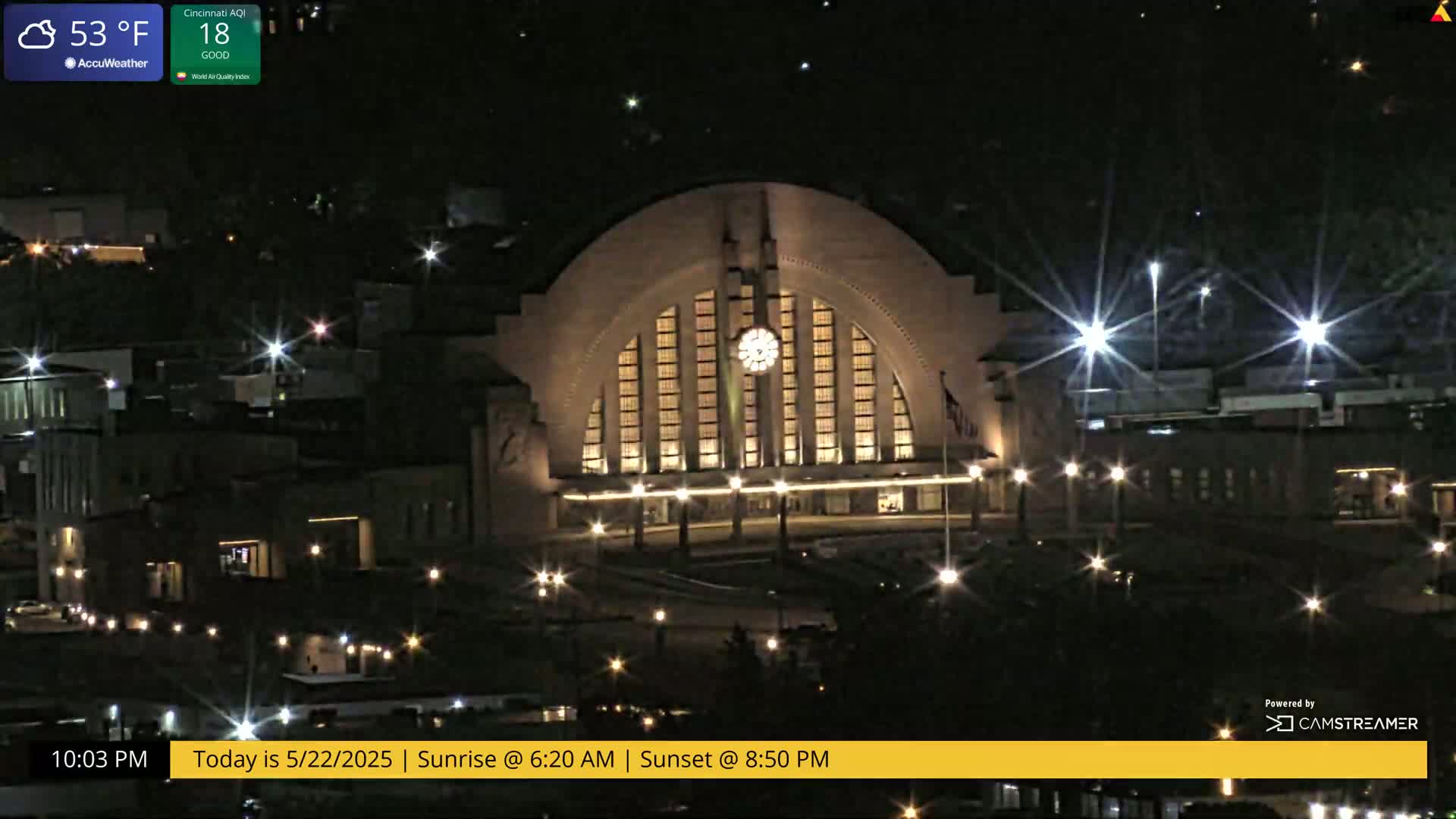 A large, illuminated building, possibly a train station, is shown at night under a clear sky, with a temperature of 53°F.