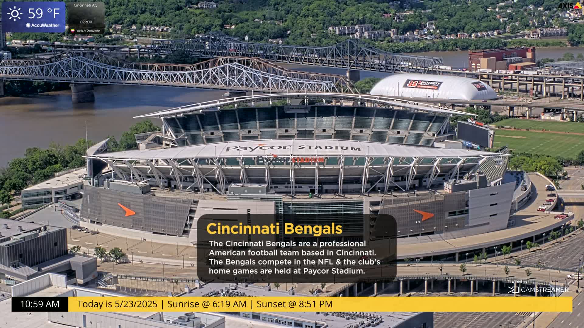 An aerial view of Paycor Stadium on a partly sunny day, with a river and bridge visible in the background.