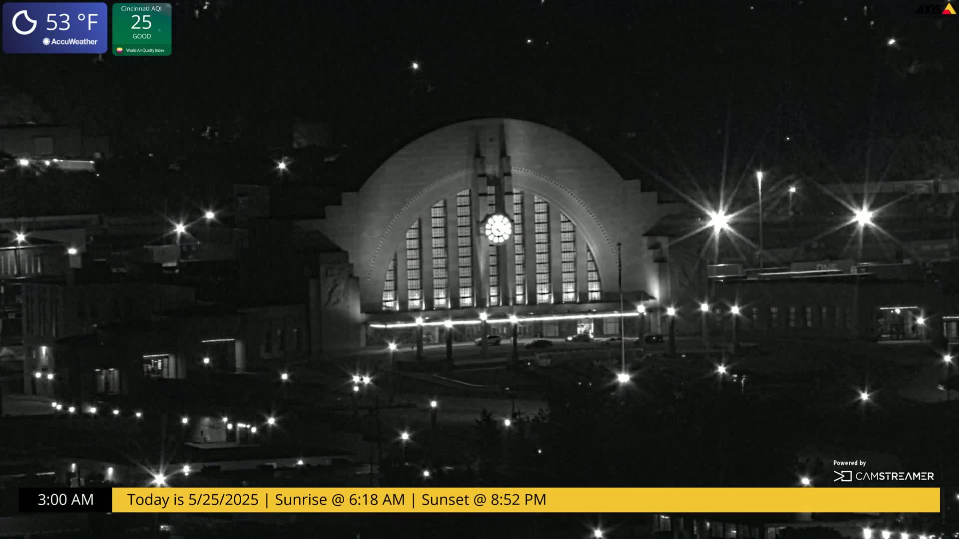 A large, illuminated building with a semicircular facade and clock is seen at night, under clear skies with a temperature of 53°F.