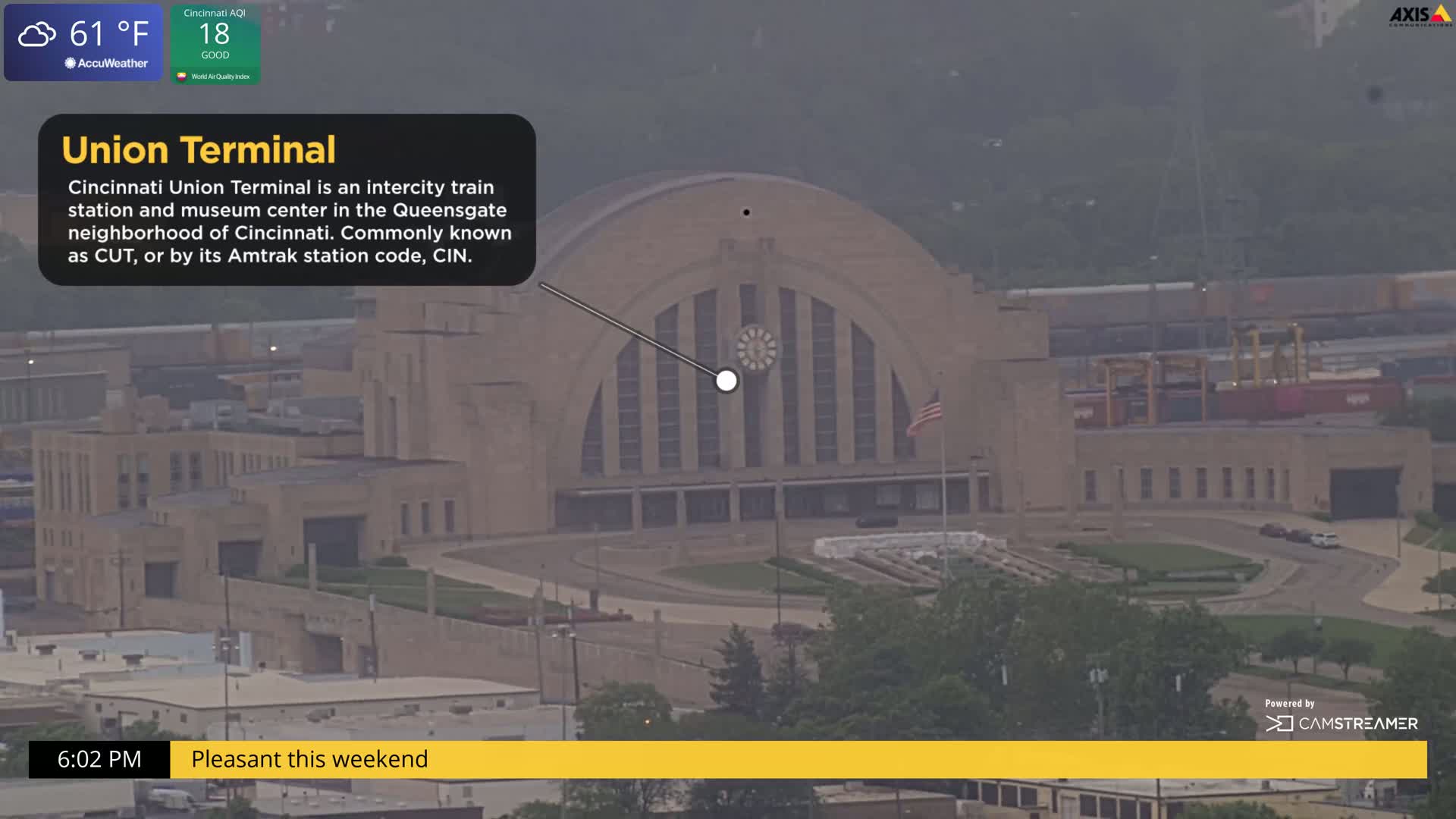 A hazy, high-angle view shows Cincinnati Union Terminal, a large, light-brown Art Deco style building with a curved roof and a clock on its facade.