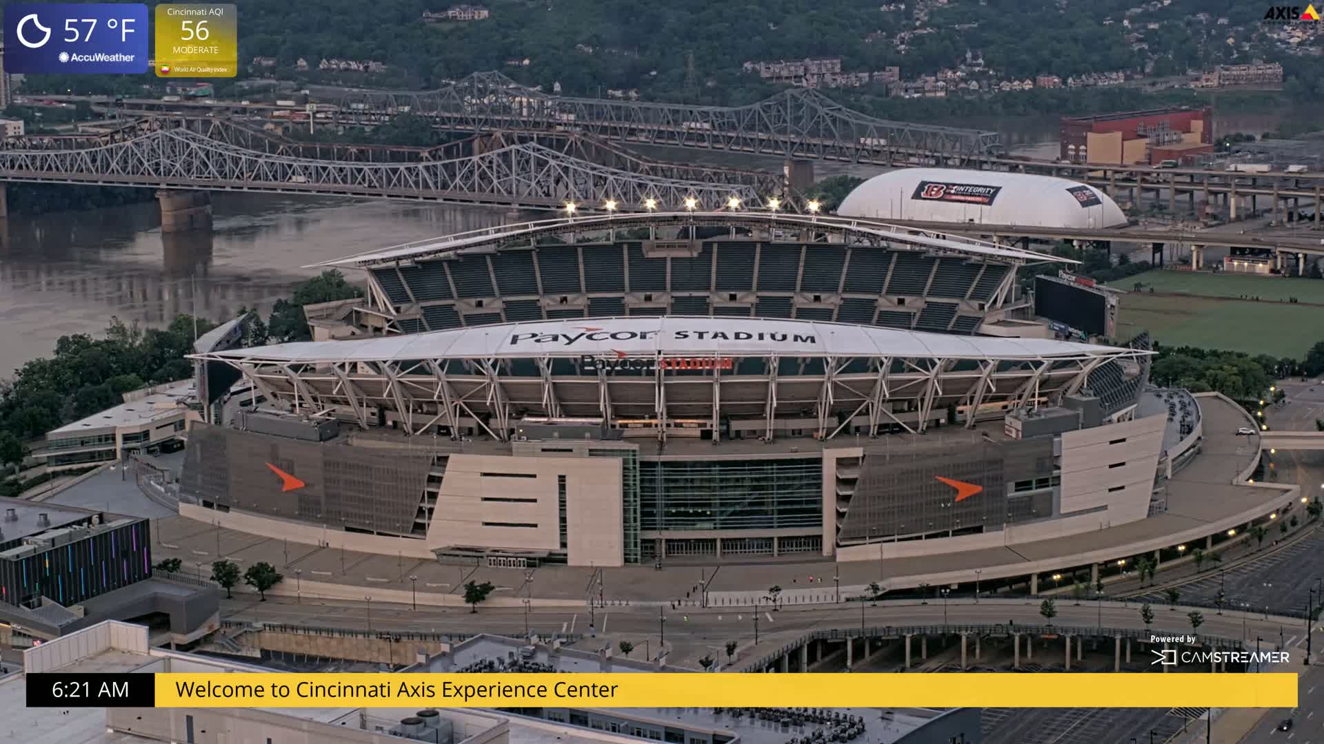 An aerial view of Paycor Stadium at dawn, showing a river and bridge in the background under mostly clear skies.