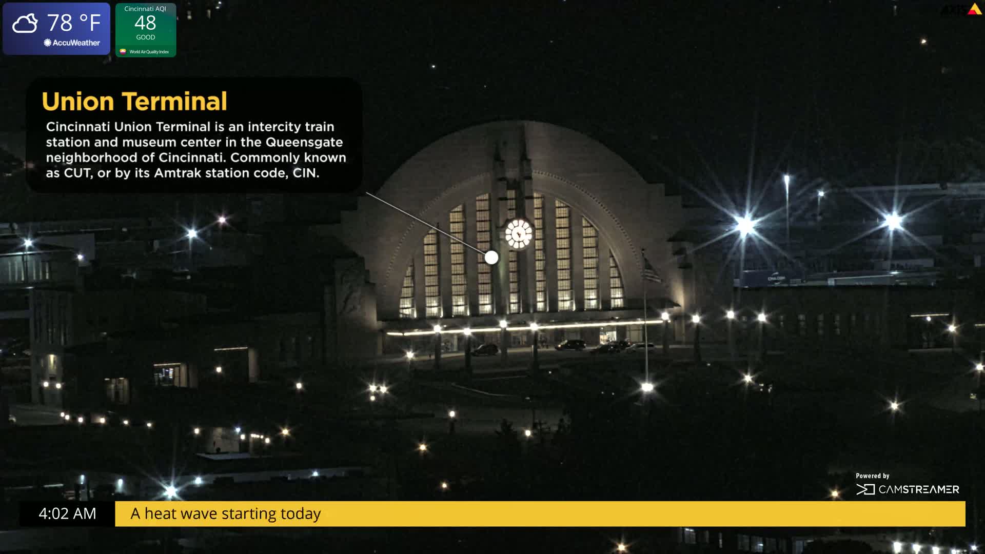 A large, illuminated art deco building, possibly a train station, is shown at night under a clear sky.