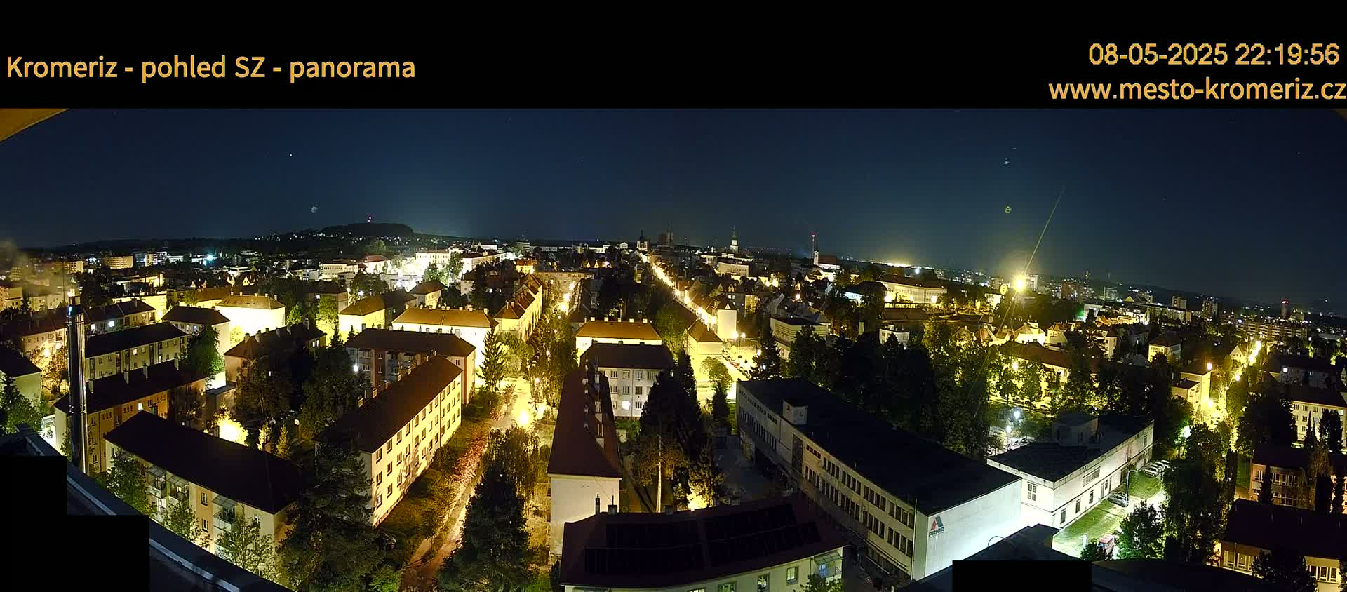 A panoramic nighttime view of a city illuminated by streetlights, under a clear, dark sky.