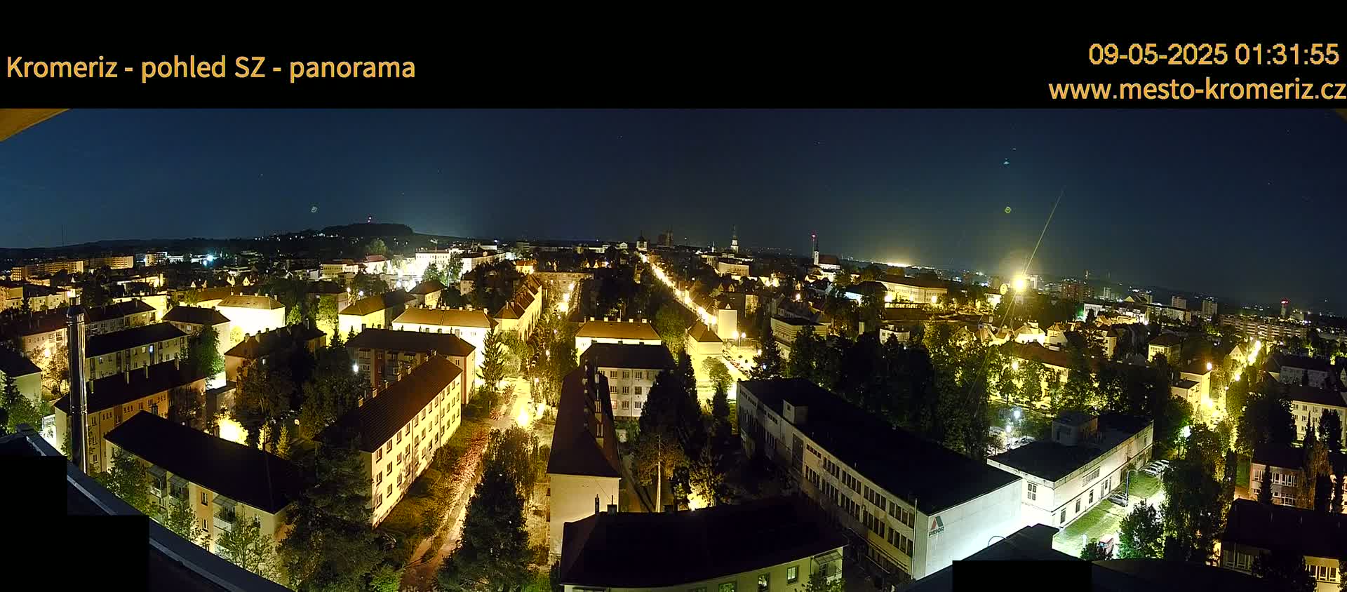 A nighttime panoramic view of a city illuminated by streetlights under a clear, dark sky.