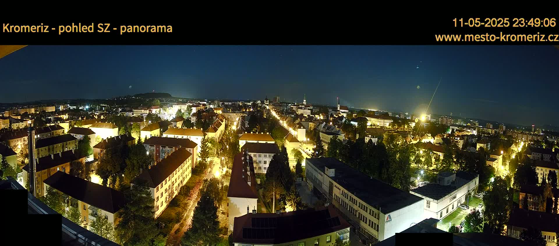 A nighttime panoramic view of a city illuminated by streetlights under a clear, dark sky.