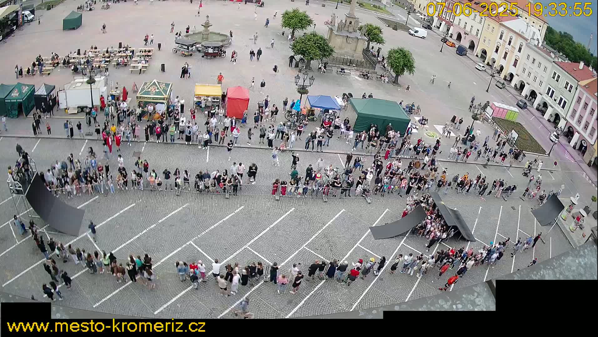 A large crowd surrounds several ramps set up in a town square on a partly sunny day.