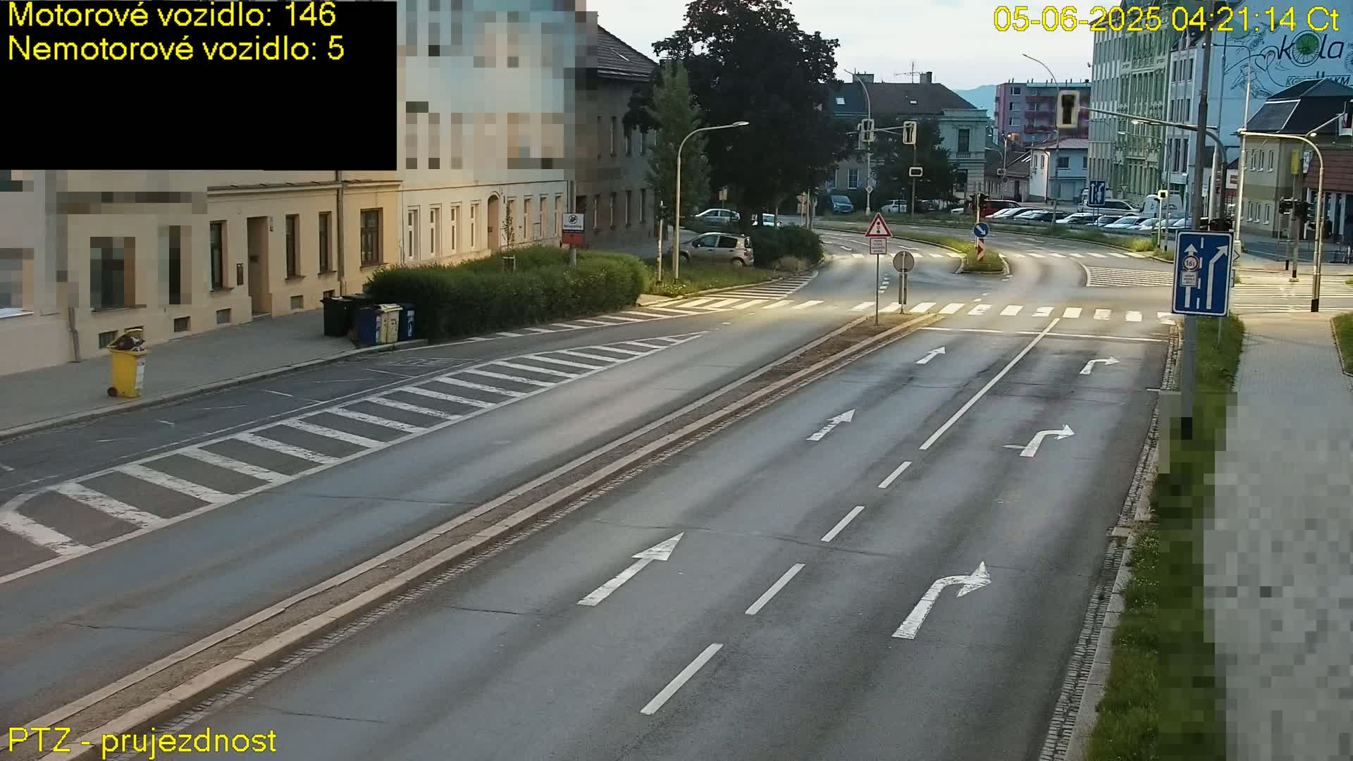 A mostly empty road intersection with pedestrian crossings and streetlights at twilight.