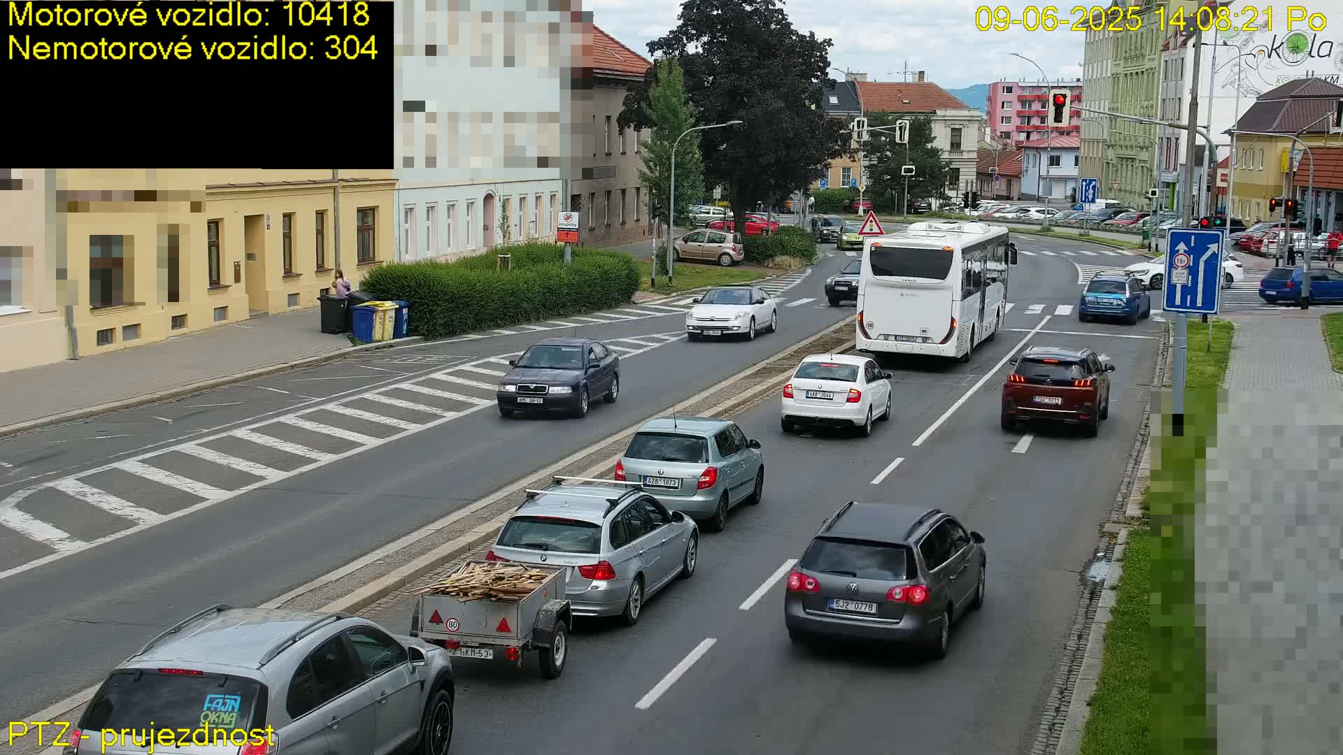 Several cars and a bus are driving on a city street on a partly sunny day.