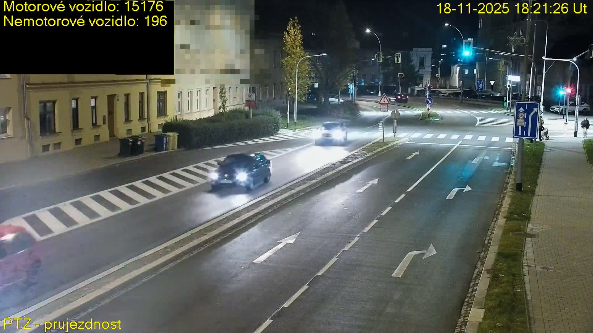 A sunny day shows a street scene with a road under construction, featuring a dug-up section cordoned off by a temporary fence.