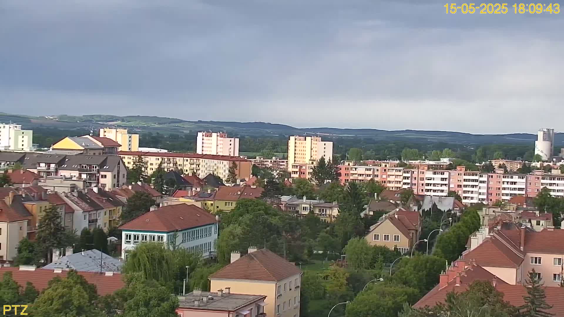 A sprawling residential area with multi-story apartment buildings and smaller houses, under a mostly cloudy sky.