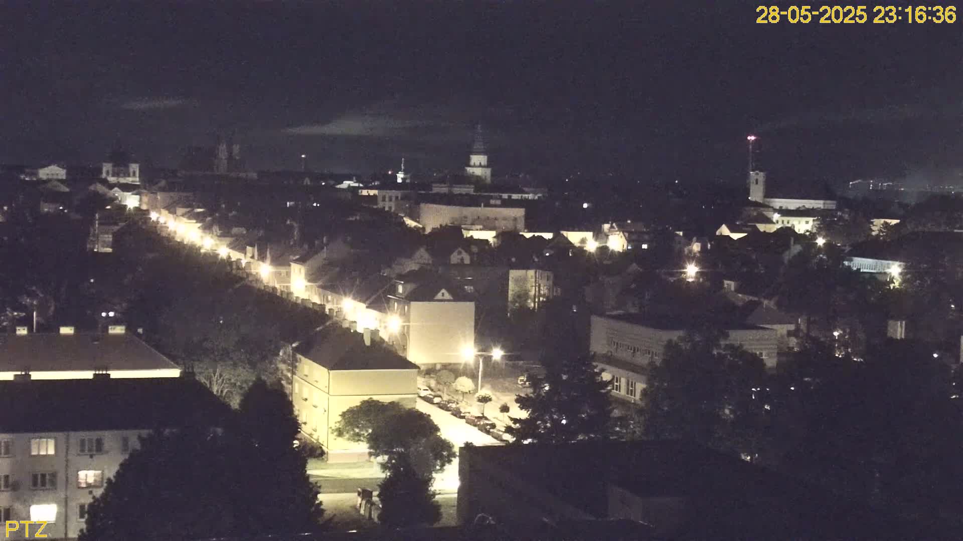 A nighttime, high-angle view of a town with illuminated streets and buildings under a dark sky.