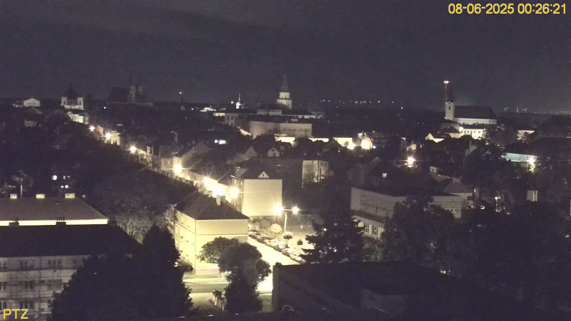 A nighttime, high-angle view of a town with streetlights illuminating buildings and roads.