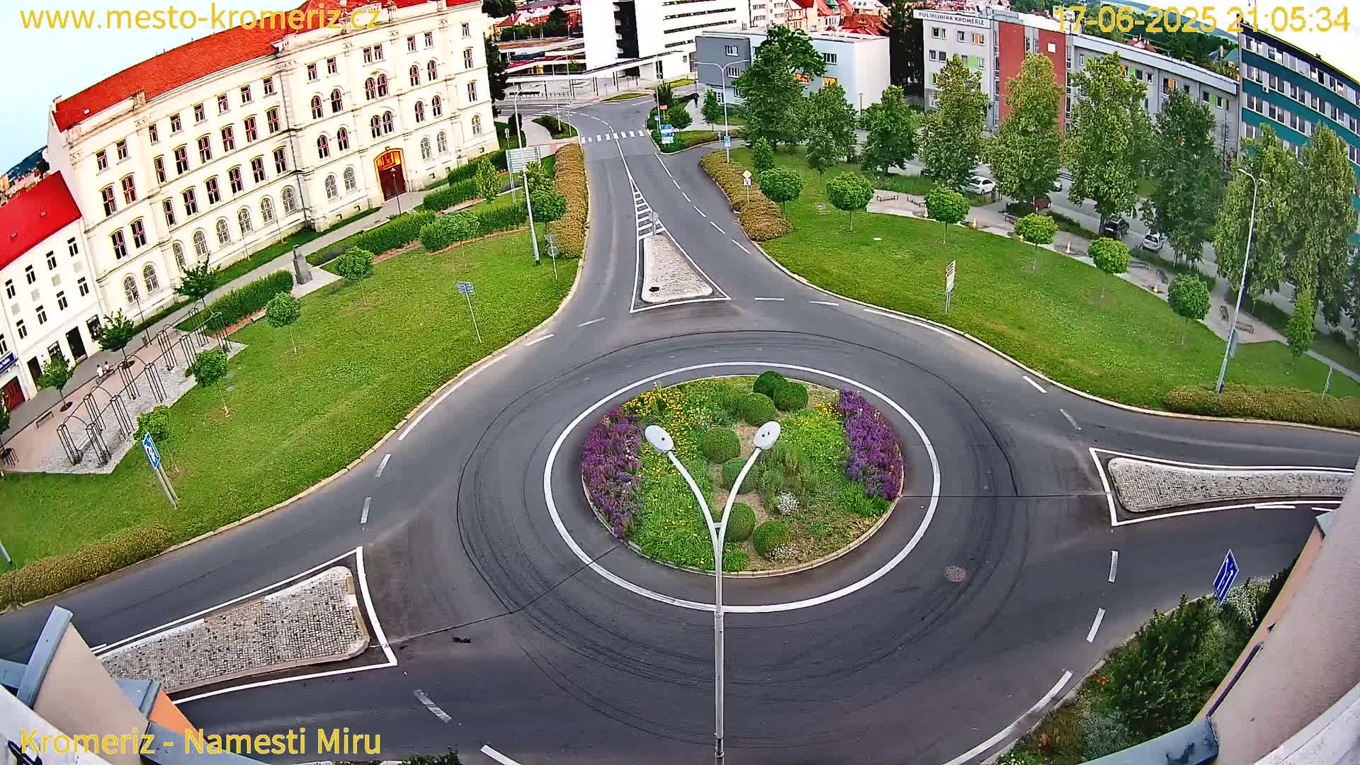 An aerial view shows a roundabout surrounded by a grassy area and buildings, under twilight conditions.