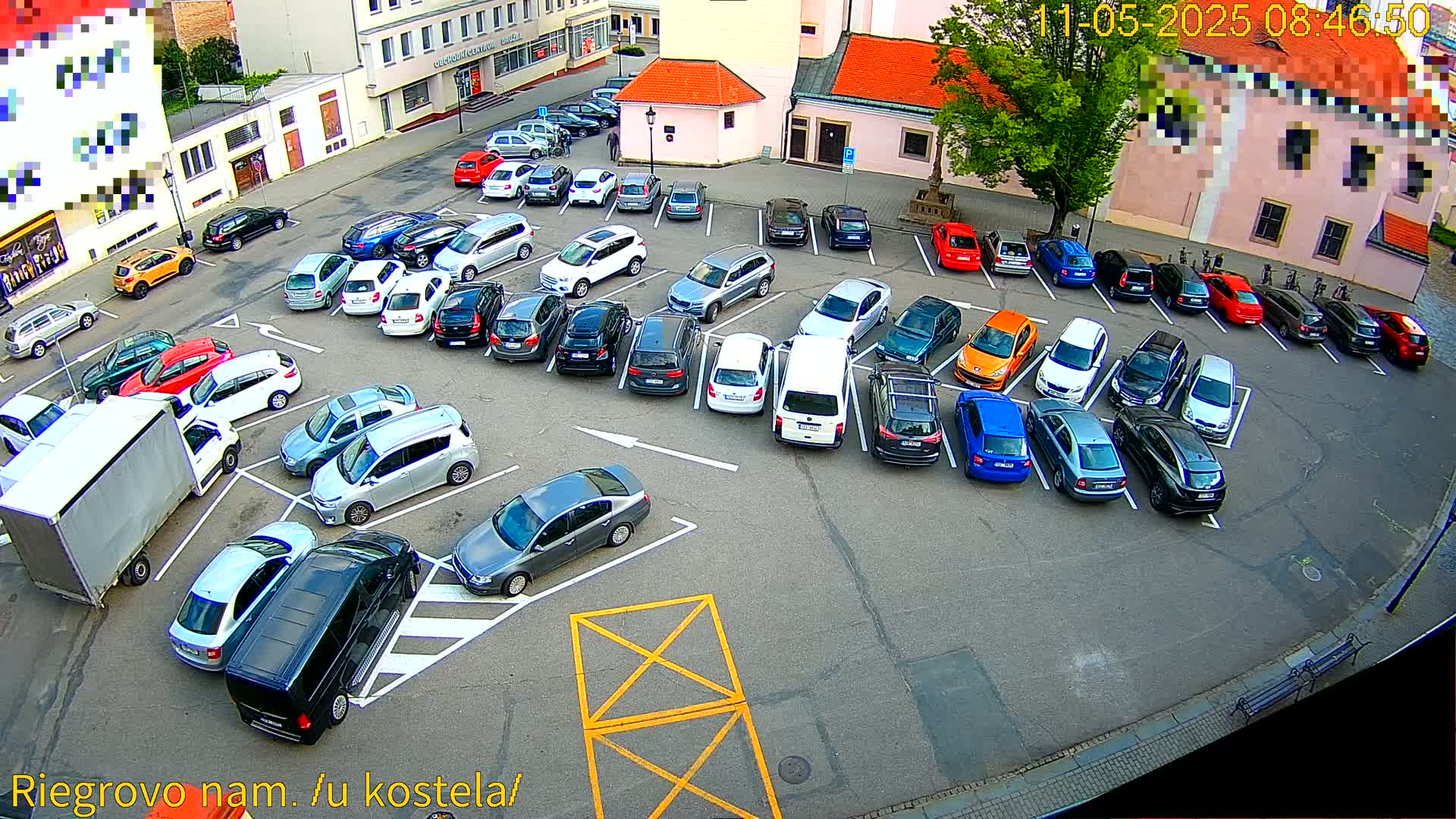 An aerial view shows a parking lot filled with various cars on a sunny day.