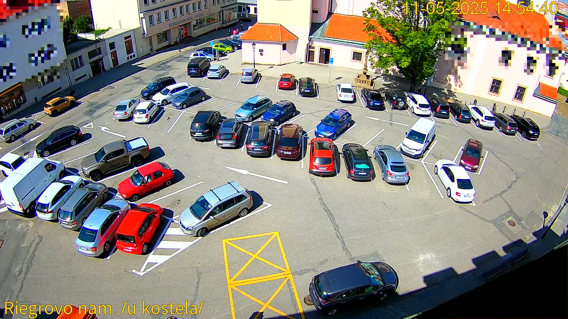 A sunny day reveals a full parking lot with numerous cars parked in various spaces.