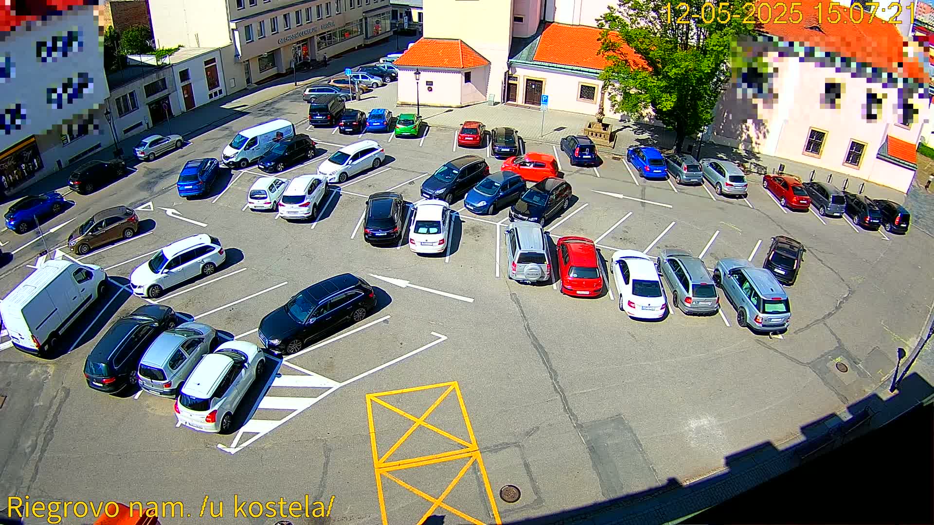 A sunny day shows numerous cars parked in a lot next to a building.