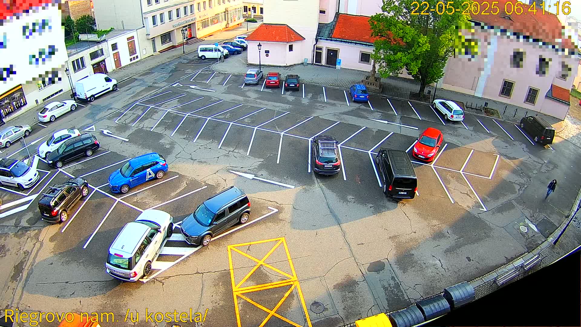 An aerial view of a mostly empty parking lot with several cars parked, under a sunny sky.