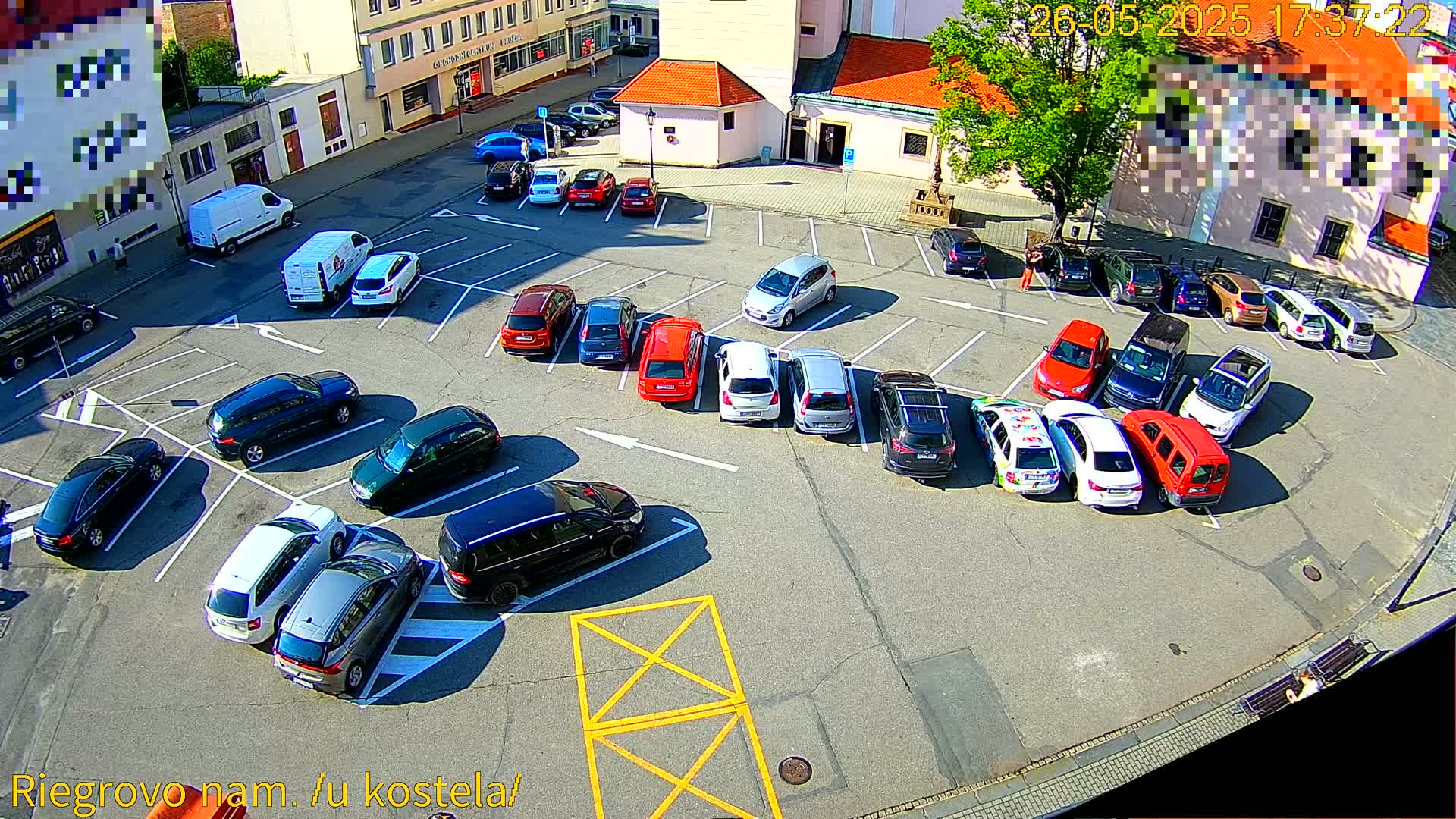 A sunny day view of a mostly full parking lot with numerous cars parked in various spaces.