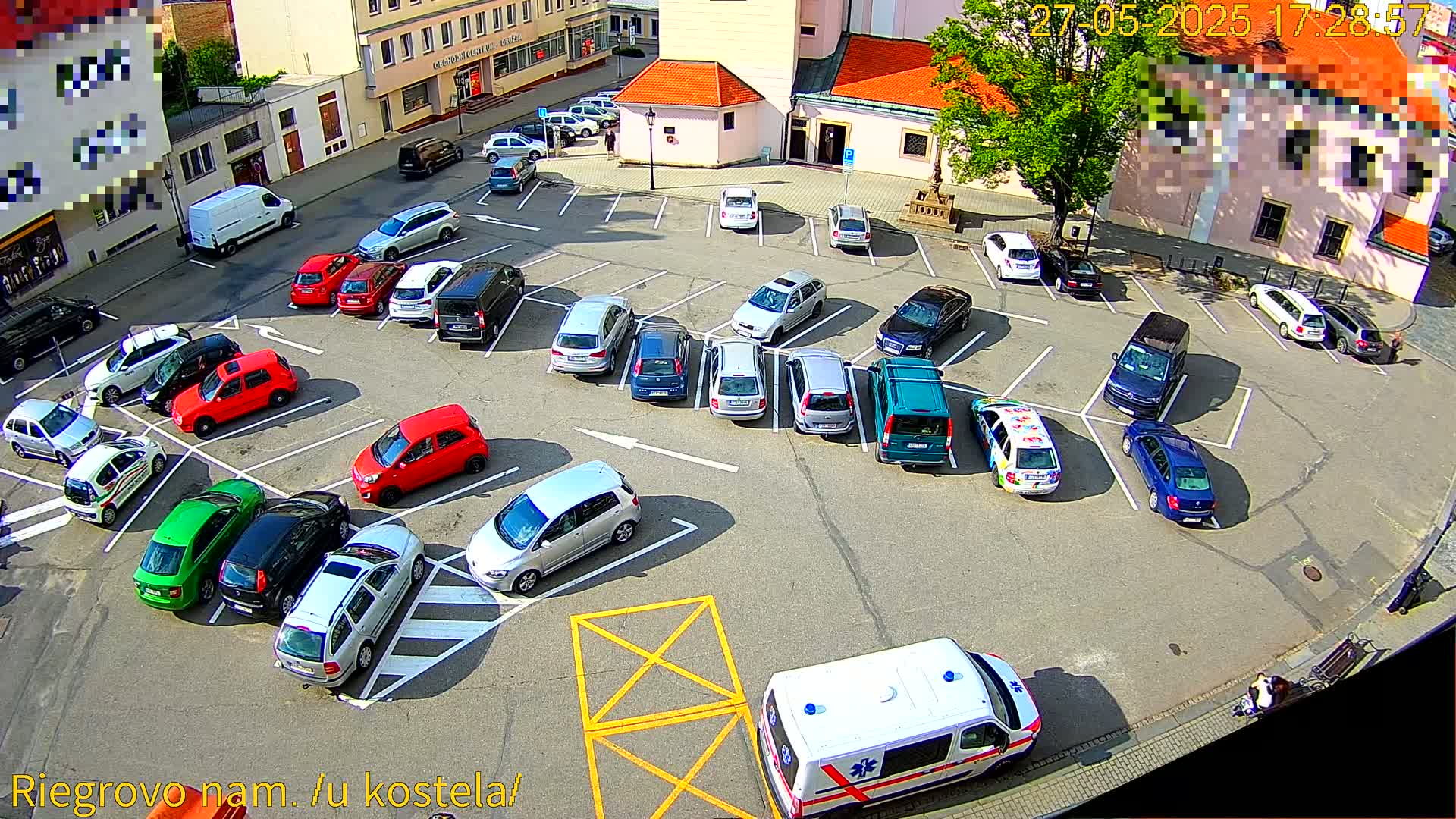 An aerial view of a mostly full parking lot on a sunny day with an ambulance parked nearby.