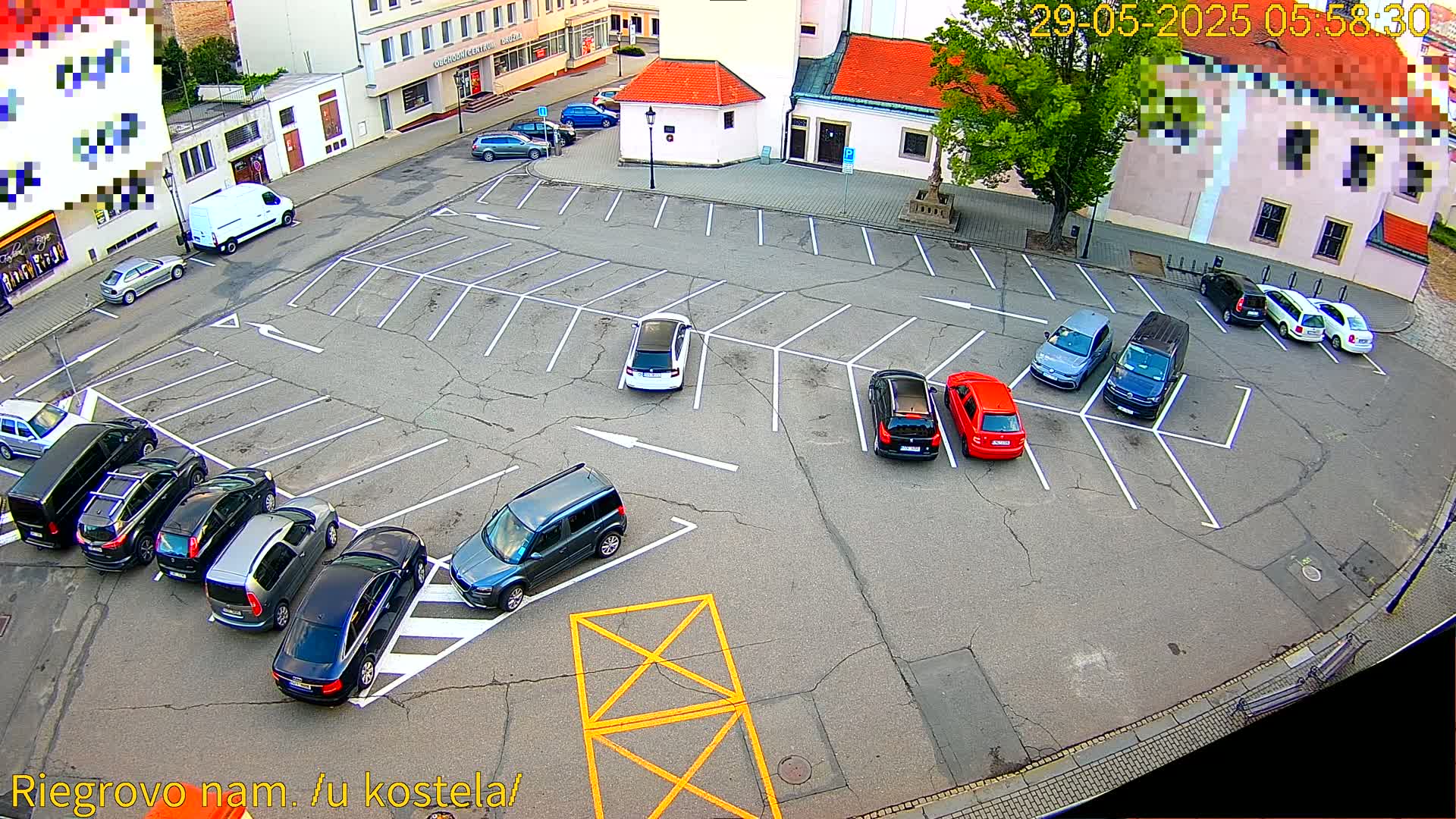 An asphalt parking lot with numerous cars parked in marked spaces, under a partly cloudy sky.