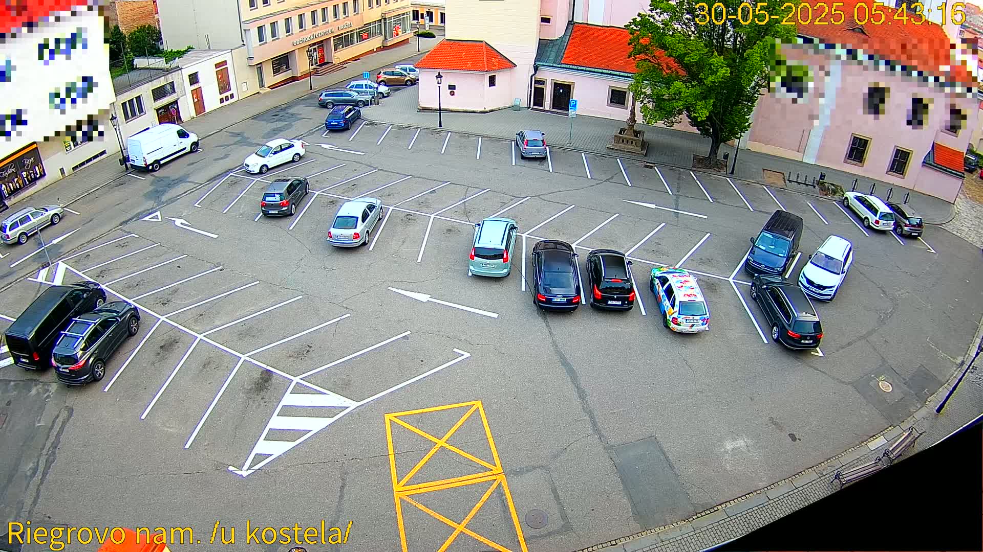 An asphalt parking lot with numerous cars parked under a partly cloudy sky.