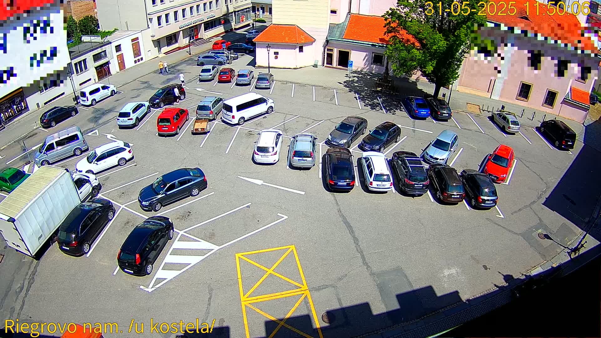 A mostly full parking lot with numerous cars parked under a sunny sky.