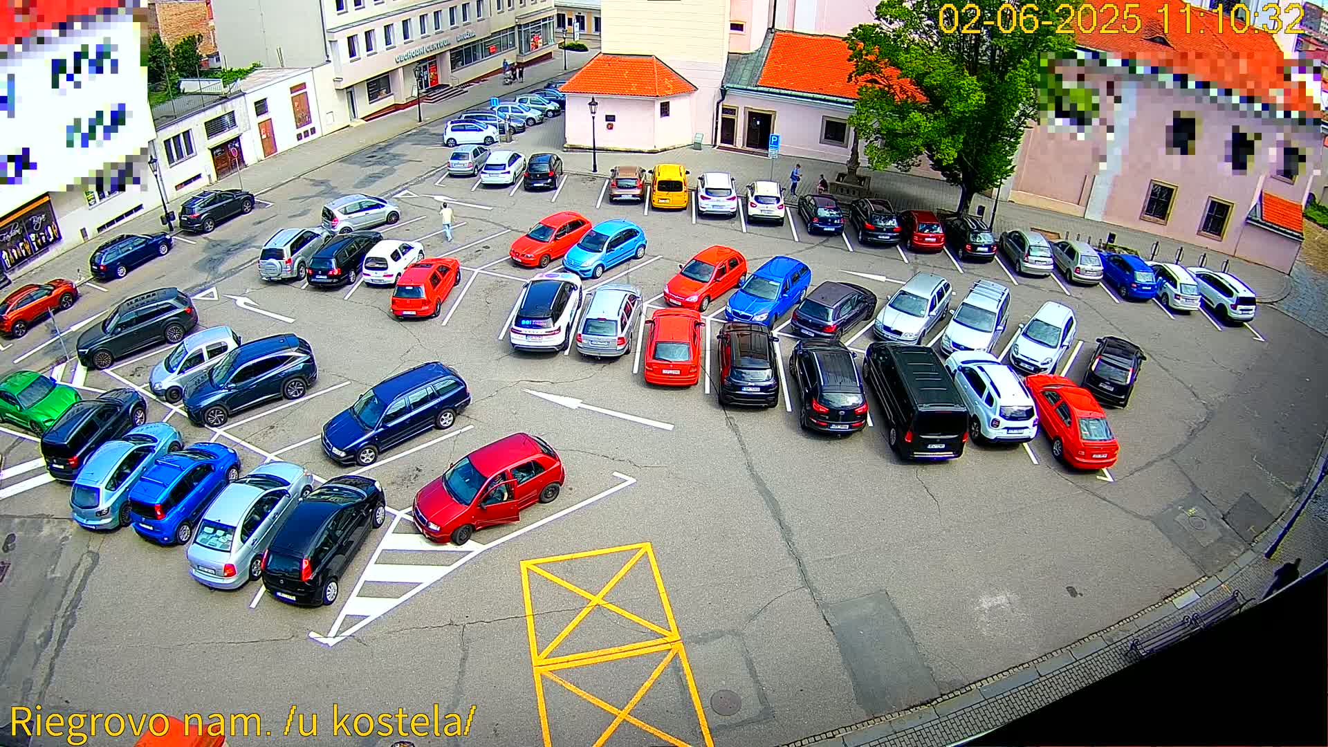 A mostly full parking lot with numerous cars of various colors and models parked on a sunny day.