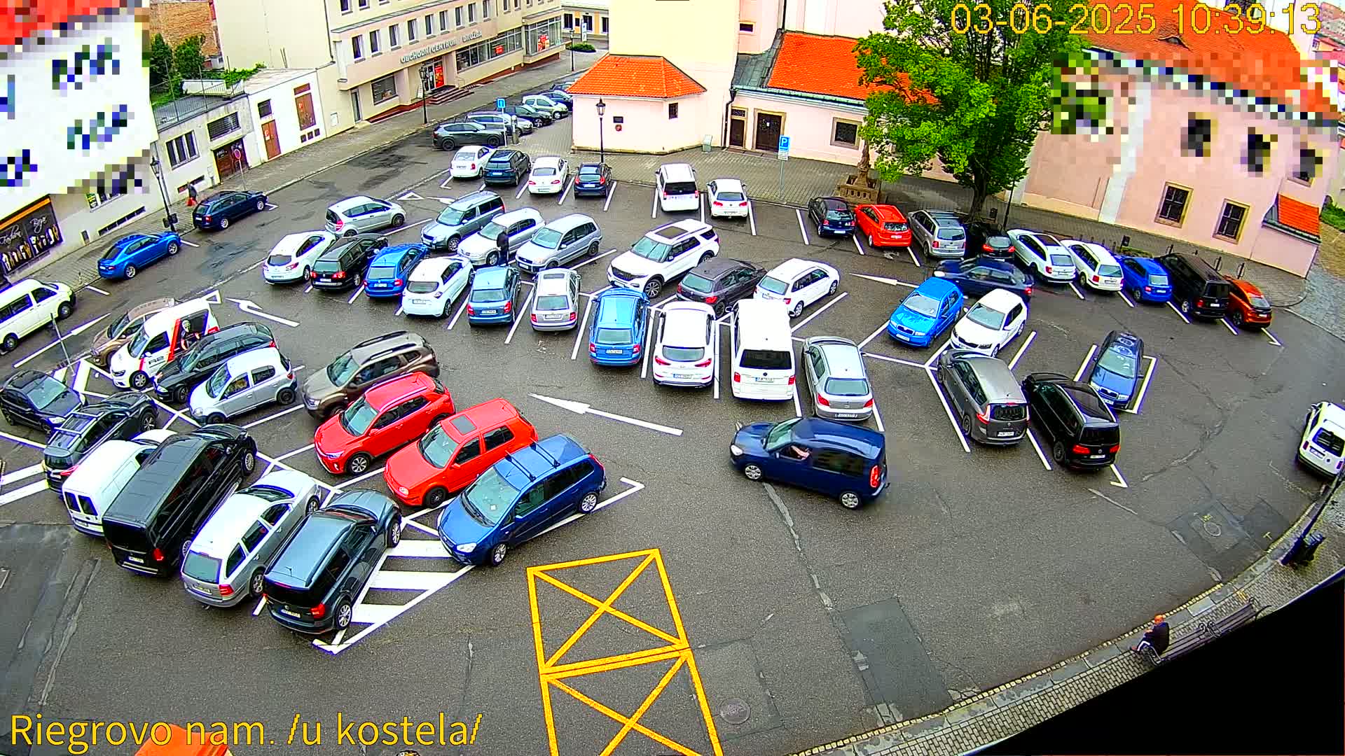 An aerial view of a crowded parking lot filled with various cars on a mostly overcast day.