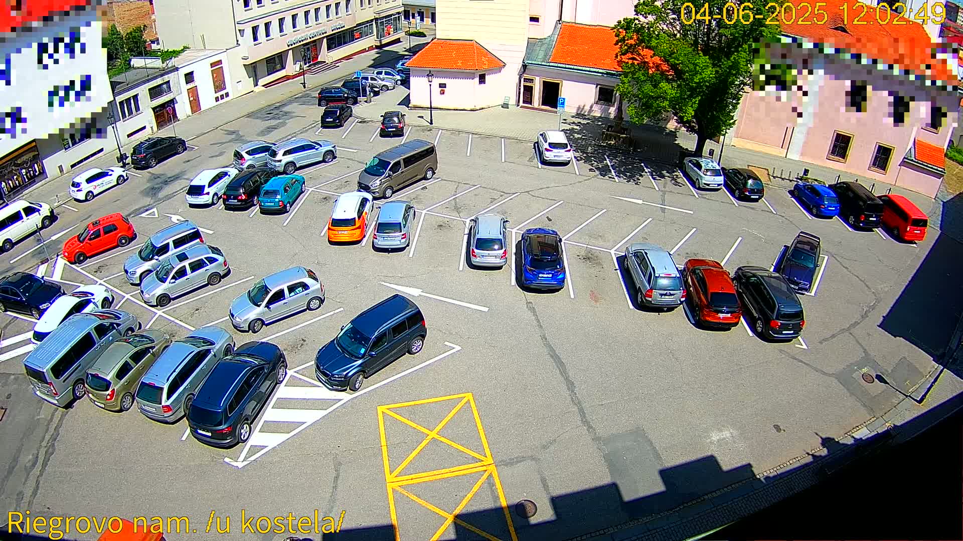 A parking lot filled with various cars is viewed from above on a sunny day.