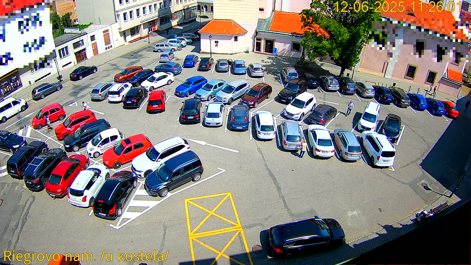A mostly full parking lot with a variety of cars parked in it on a sunny day.