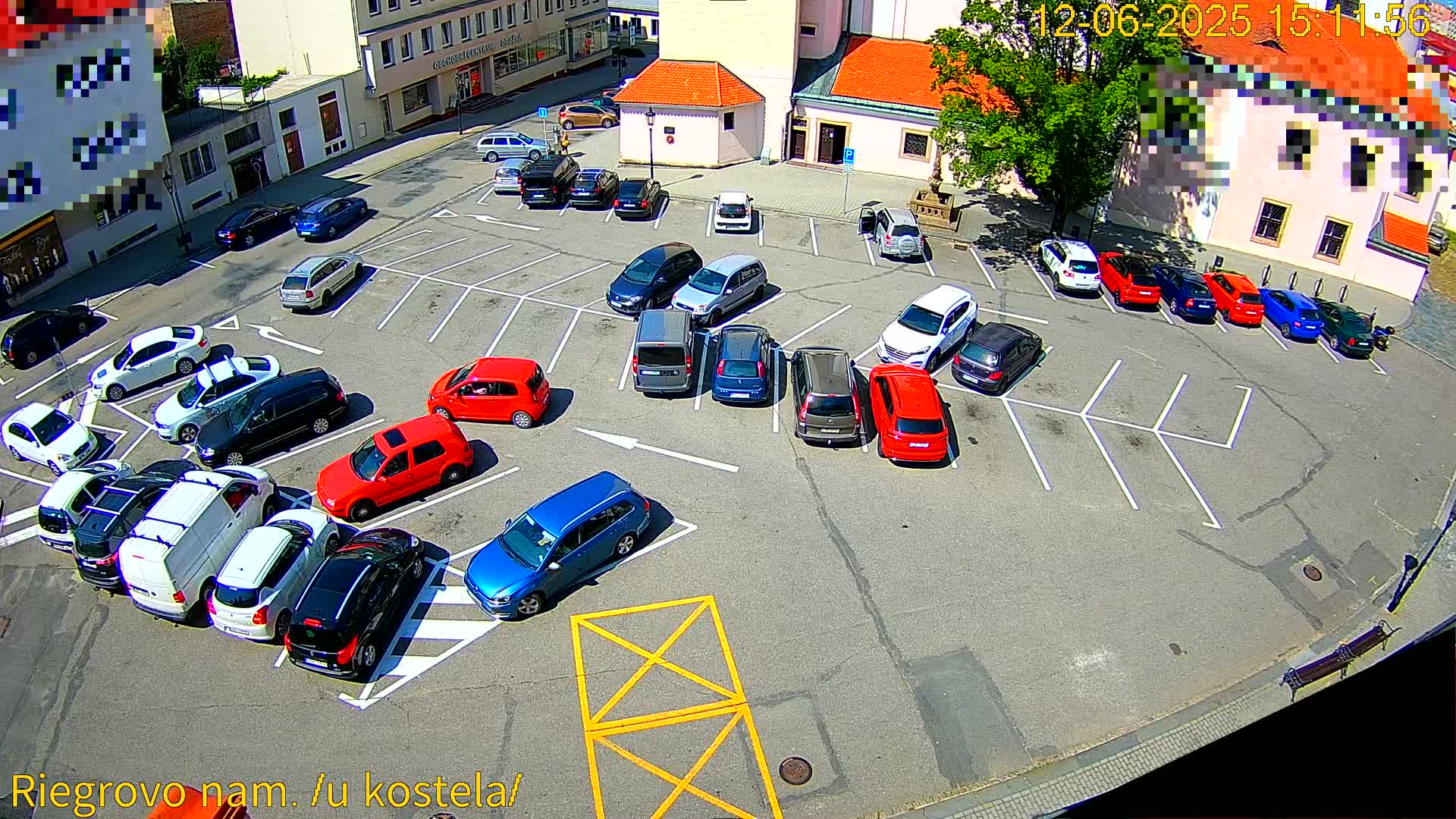 A sunny outdoor parking lot is filled with numerous cars parked in various spots.