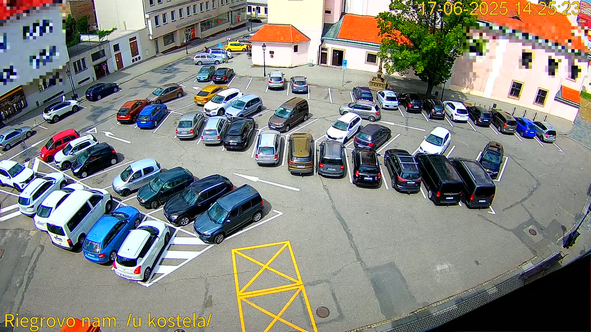 A sunny day shows a full parking lot with many cars parked in various spaces.