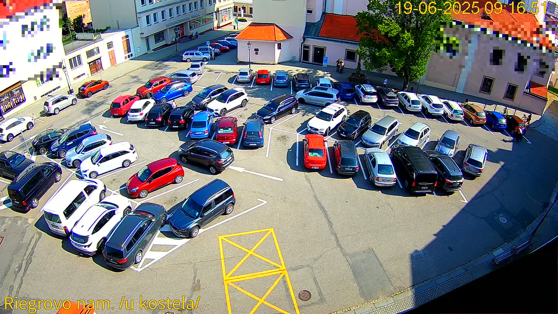 A sunny day shows a parking lot full of various cars parked in a somewhat organized manner.