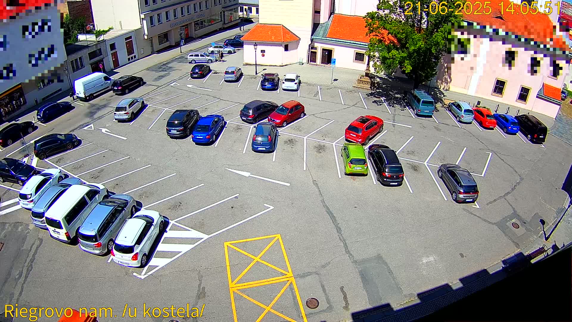 A sunny day reveals a full parking lot with numerous cars parked in marked spaces, surrounding a church-like building.