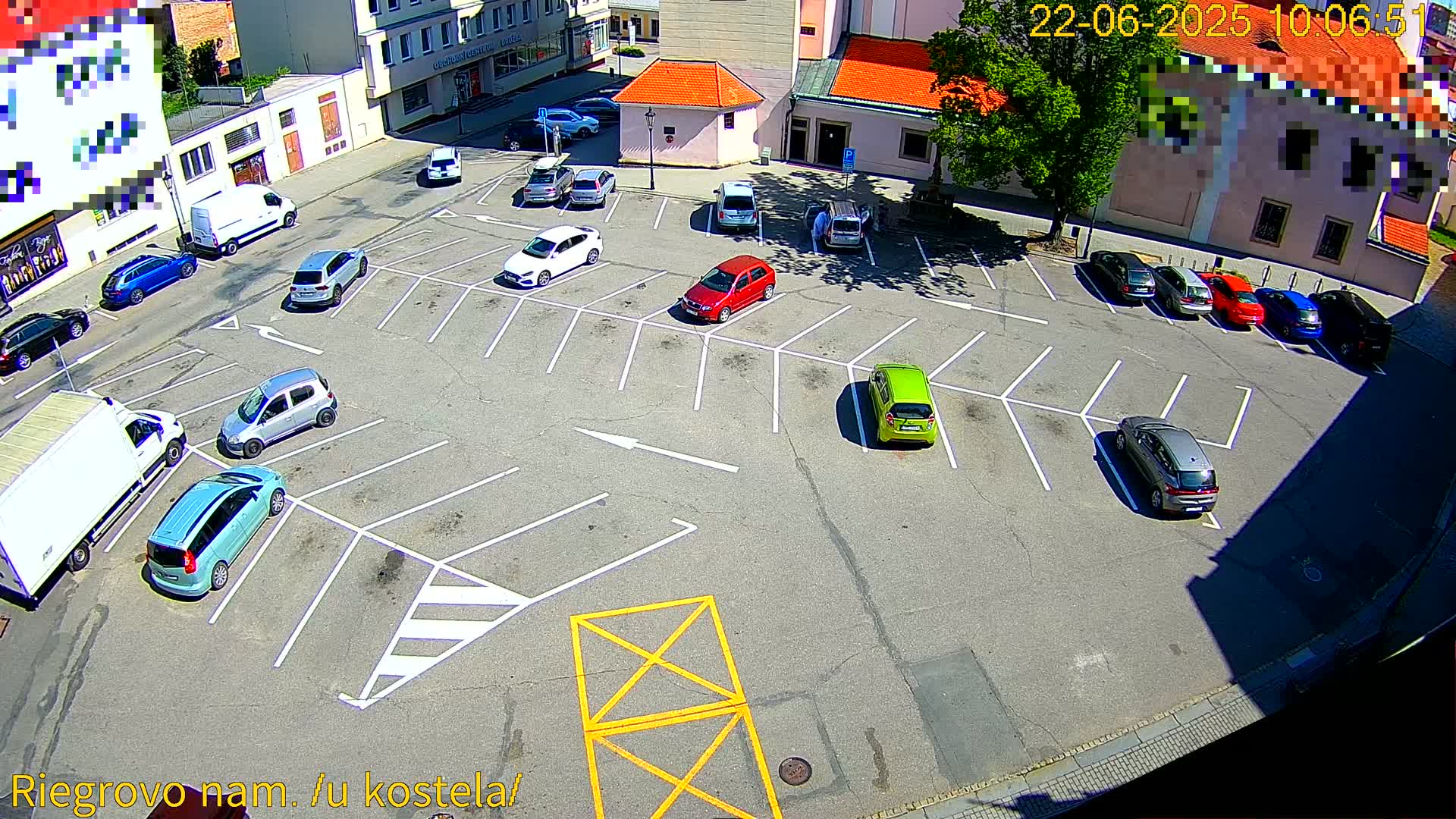A mostly empty parking lot with several cars parked in it on a sunny day.