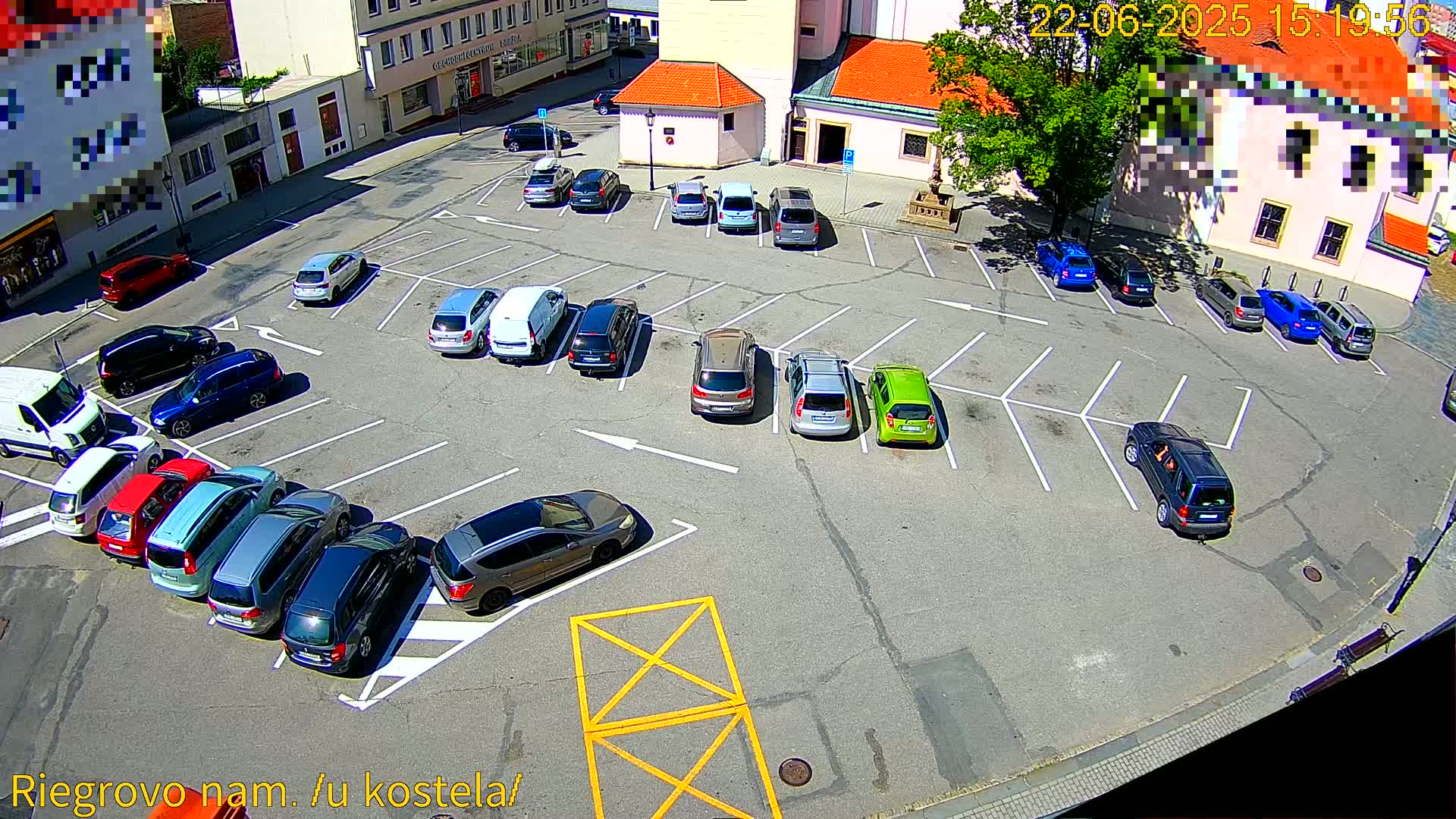 A sunny day reveals a mostly full parking lot surrounded by buildings.