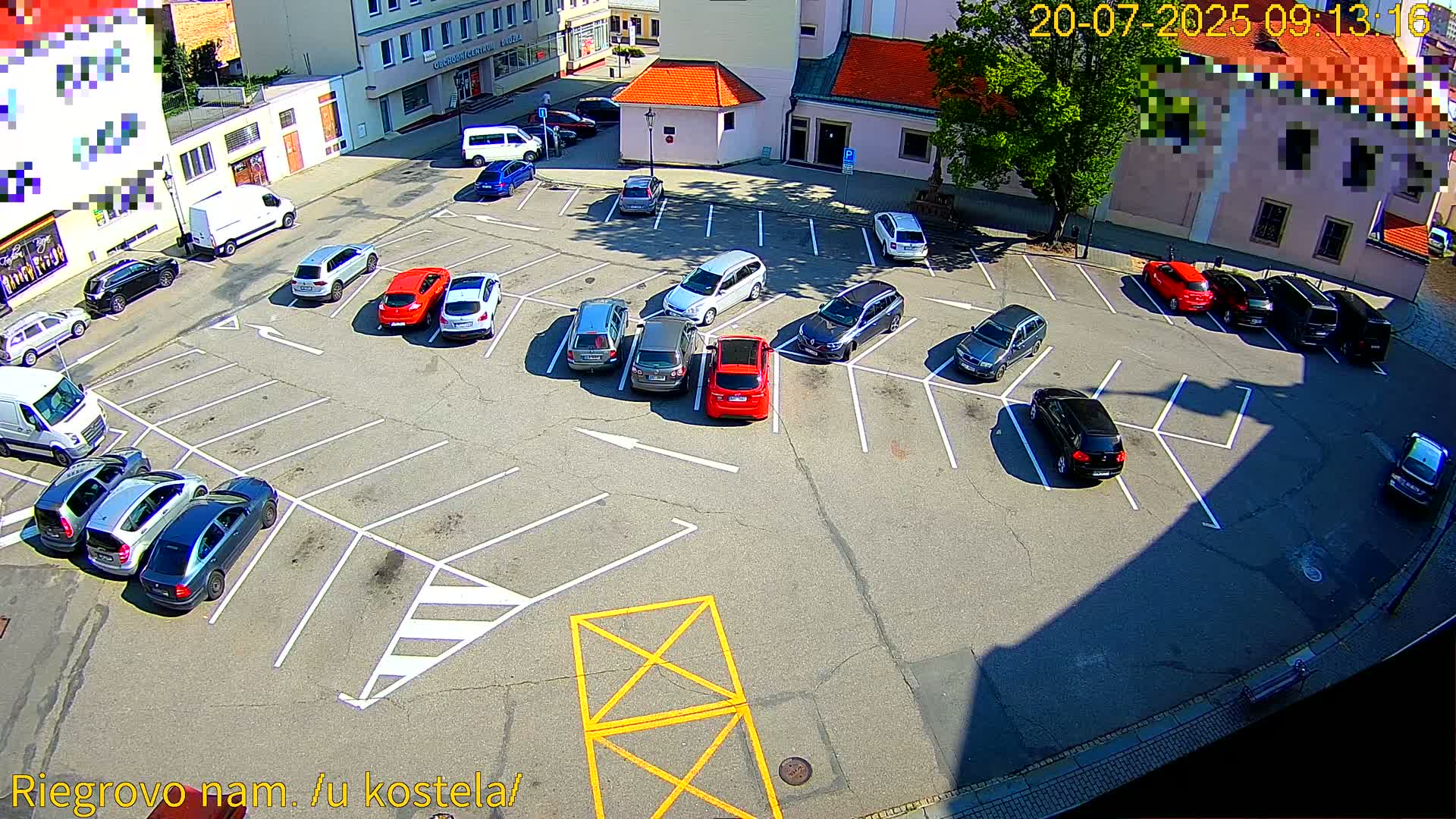 A sunny day shows a mostly full parking lot with various cars parked in designated spaces.