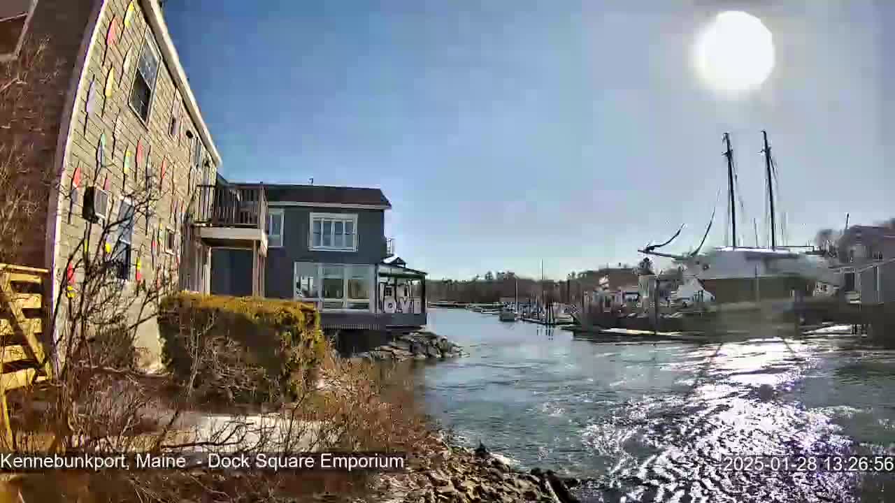 A sunny day reveals a waterfront scene with buildings, a docked sailboat, and a waterway.