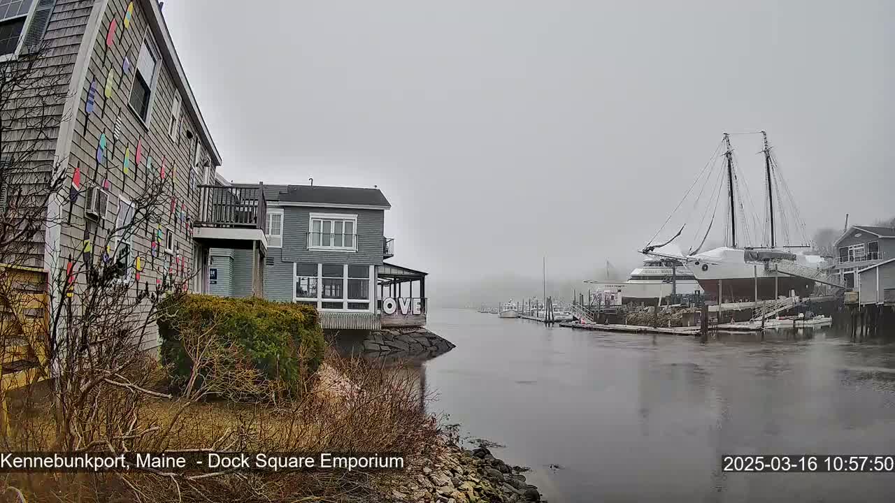 A foggy waterfront scene shows a gray building with colorful accents, another gray building with "LOVE" on the side, docked boats, and a large sailboat.
