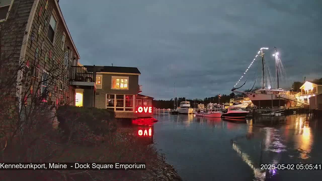 A waterfront scene at dusk shows a building with a "LOVE" sign, several boats in a calm harbor, and a large sailboat docked nearby.