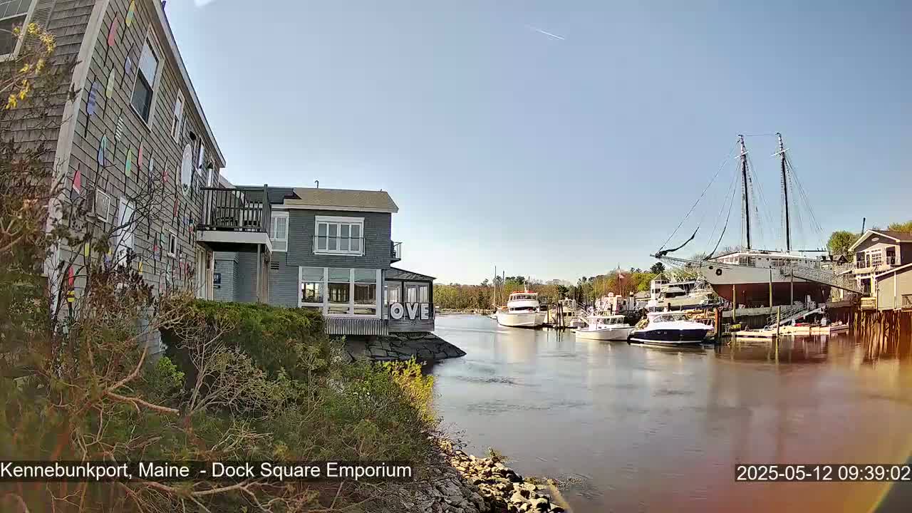 A waterfront scene on a sunny day shows several boats docked near buildings, one of which displays a large "LOVE" sign.