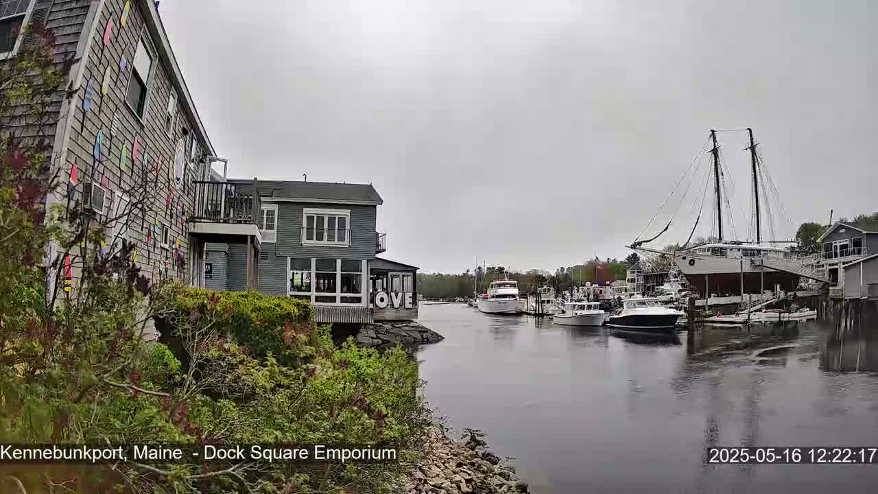 A gray day reveals a waterfront scene with several boats moored in a calm waterway, alongside buildings featuring a colorful exterior and a sign that reads "LOVE".
