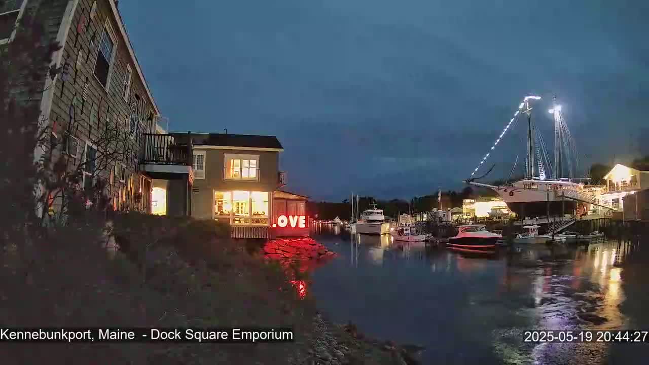 A nighttime harbor scene shows a lit-up building with a "LOVE" sign, several boats, and a large sailboat docked under a twilight sky.