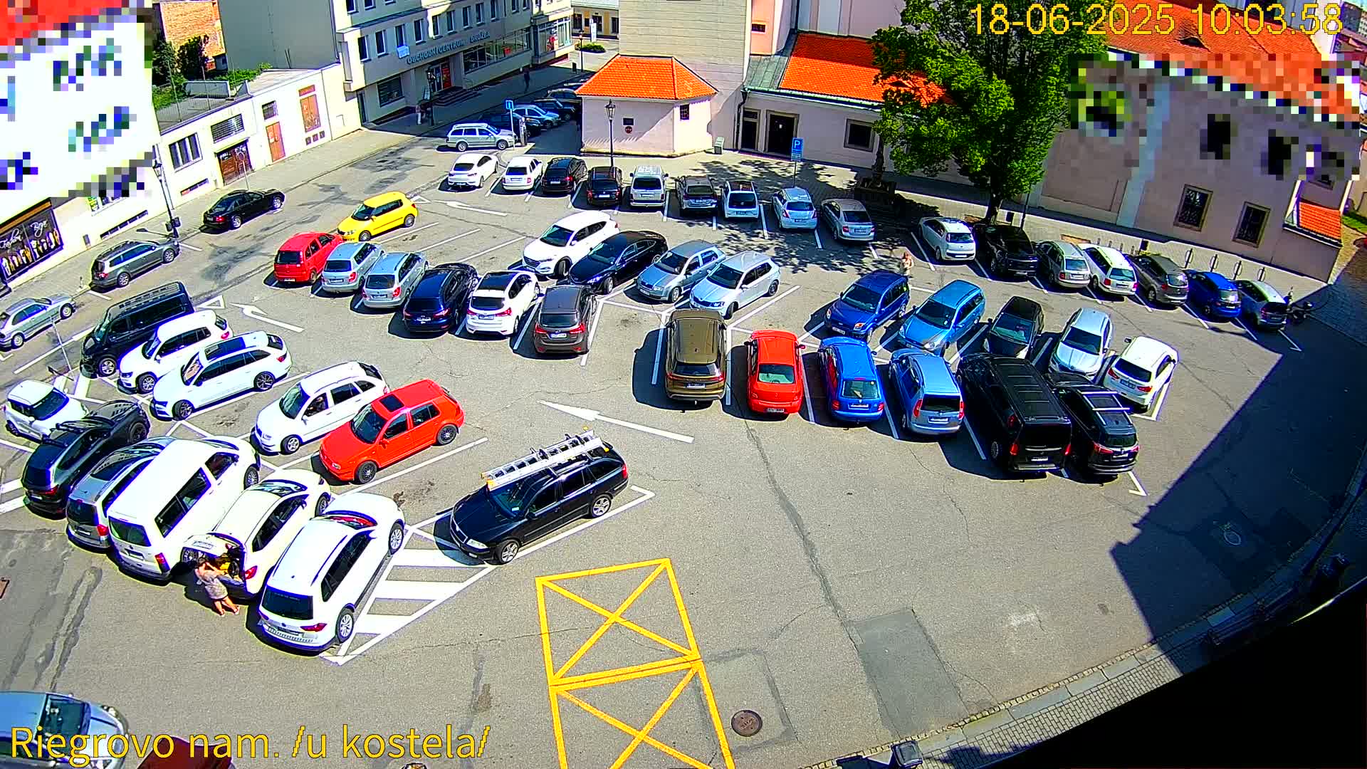 A sunny day shows a full parking lot with numerous cars parked in various colors and models.