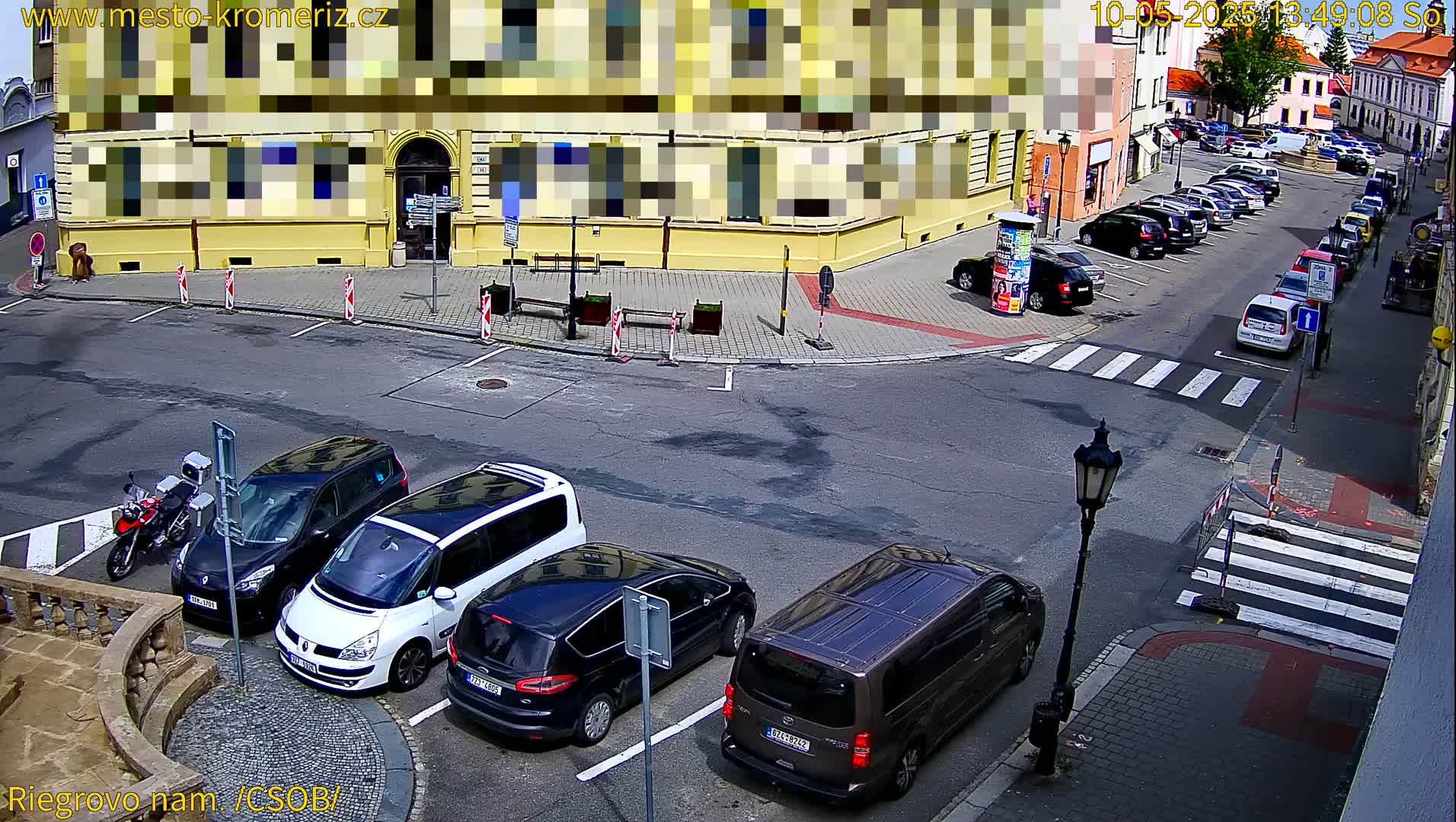 Several cars are parked in a street corner parking lot on a sunny day.