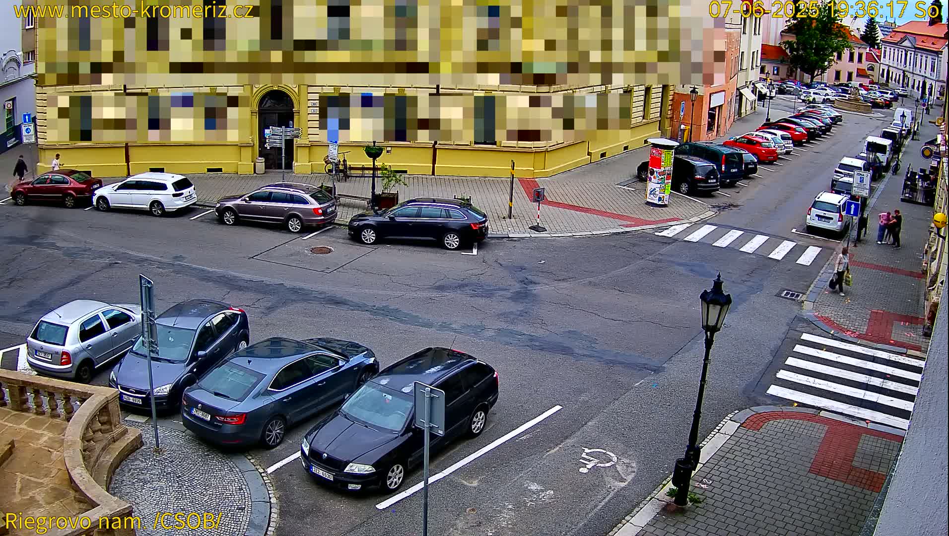 Several cars are parked in a city street intersection on a partly sunny day.
