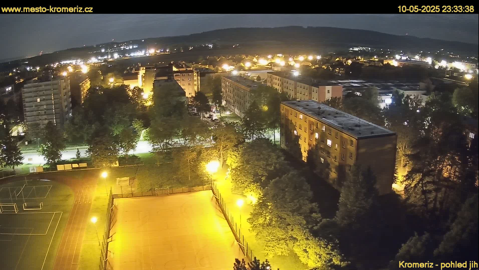 A nighttime aerial view of an apartment complex and athletic field illuminated by artificial lights.