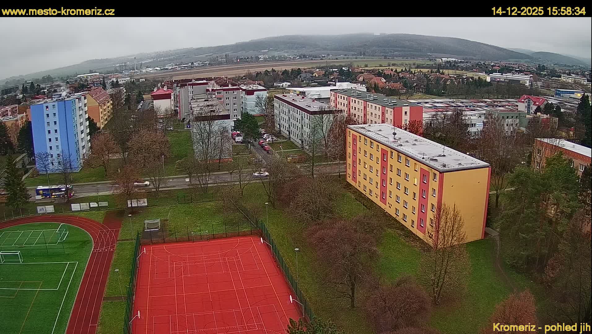 A thick fog obscures a nighttime urban scene, illuminated by glowing streetlights and scattered building lights, with a sports court faintly visible in the foreground.